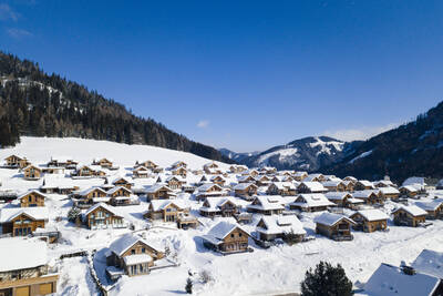 Luchtfoto van vrijstaande vakantiehuizen in de sneeuw op Alps Resorts Almdorf Hohentauern