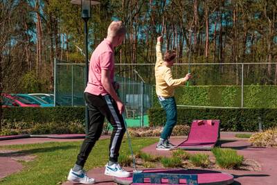 Twee mannen spelen minigolf op de minigolfbaan van vakantiepark Europarcs de Achterhoek