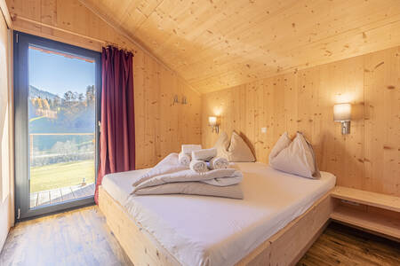 Slaapkamer met tweepersoonsbed en een chalet op Alps Resorts Bergeralm Chalets