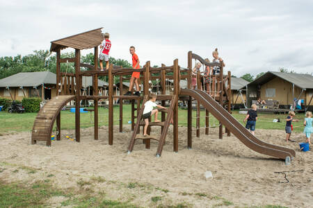 Kinderen spelen in een speeltuin op een veld met safaritenten op vakantiepark De Boshoek