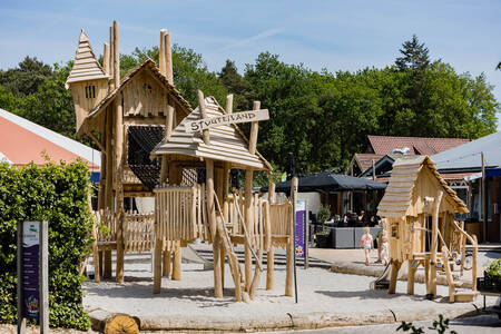 Een speeltuin met houten speeltoestellen op vakantiepark Kampeerdorp de Zandstuve