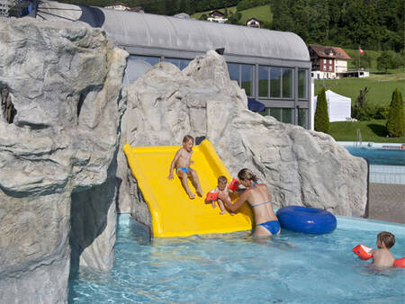 Kinderen glijden van de glijbaan in het peuterbad op Landal Alpen Resort Vierwaldstättersee