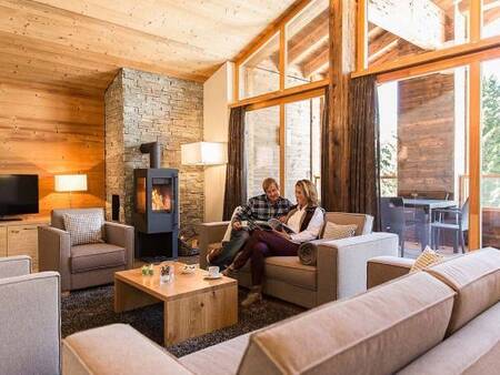 2 Mensen in de woonkamer met houtkachel van een appartement op Landal Alpine Lodge Lenzerheide