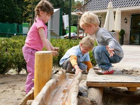 Kinderen spelen met water in de speeltuin van vakantiepark Landal De Hellendoornse Berg