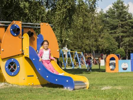 Kind glijdt van een glijbaan in een speeltuin op vakantiepark Landal Mooi Zutendaal