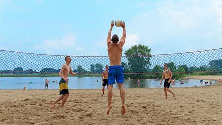 Mensen aan het volleyballen op het strand van vakantiepark Molecaten Park De Agnietenberg