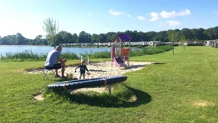 Vader met kind in een klein speeltuintje op vakantiepark Molecaten Park De Agnietenberg