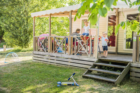Gezin zit op de overdekte veranda van een mobil home op vakantiepark RCN Le Moulin de la Pique