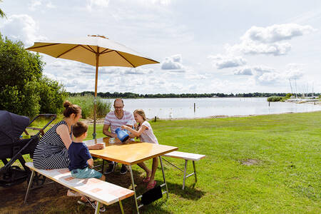Gezin aan een picknicktafel aan het Veluwemeer op vakantiepark RCN Zeewolde