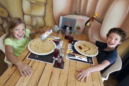 2 Kinderen eten pannenkoeken in het restaurant van vakantiepark Roompot Kustpark Egmond aan Zee