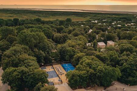 Luchtfoto met tennisbaan, speelveld en vakantiehuizen op Roompot Vakantiepark Kijkduin